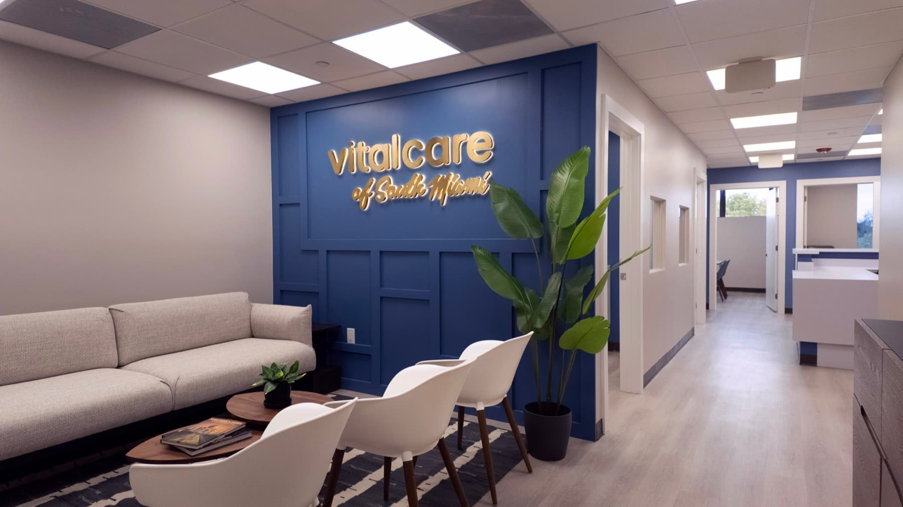 Vital Care of South Miami lobby with gold wordmark on navy panel wall, opening into clinical corridor
