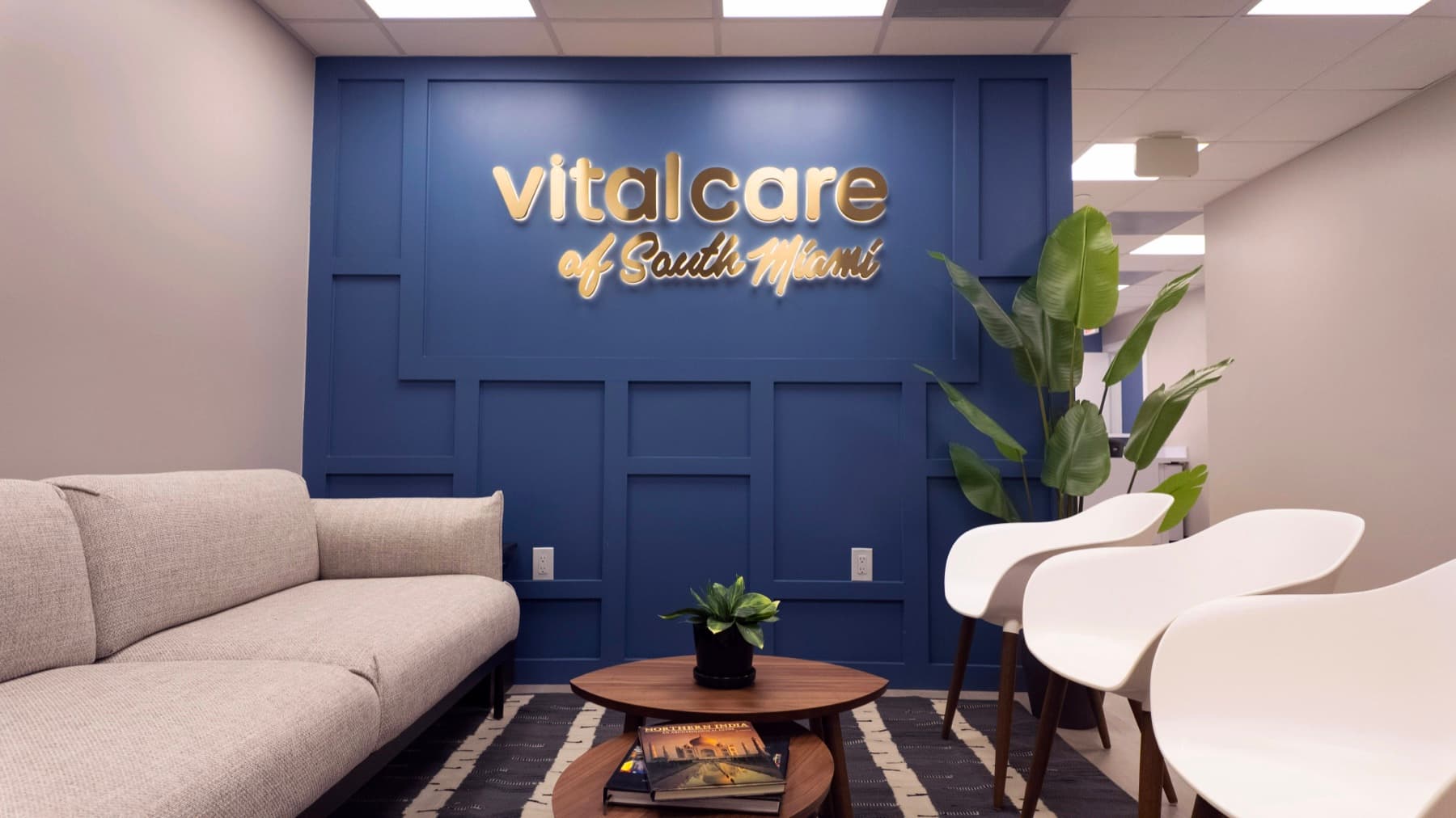 Vital Care of South Miami lobby with gold wordmark on navy panel wall, sofa and modern chairs