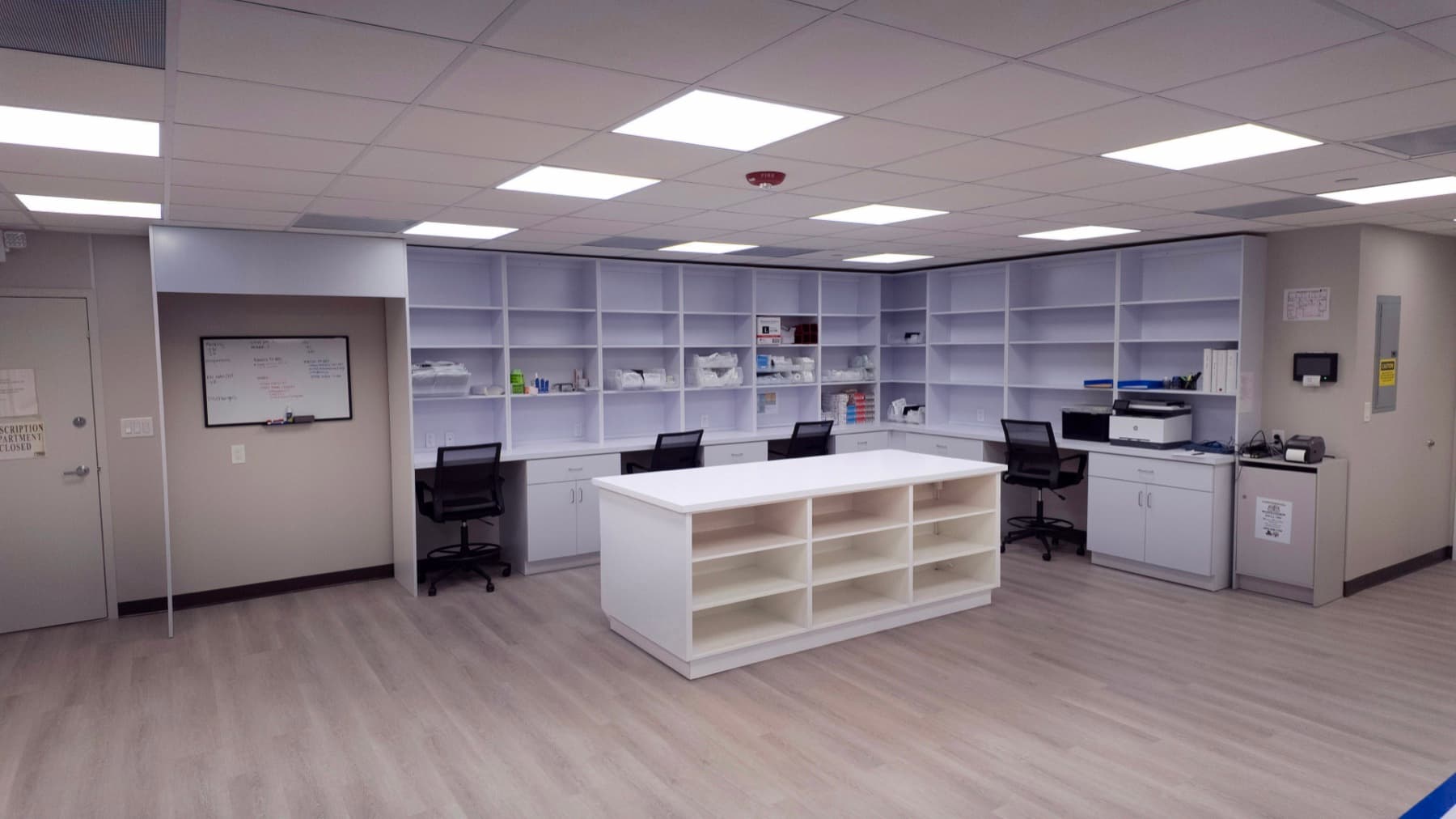 Specialty pharmacy compounding area with workstations, prep island, and inventory shelving